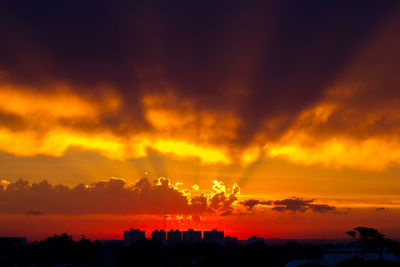 Silhouette cityscape against orange sky