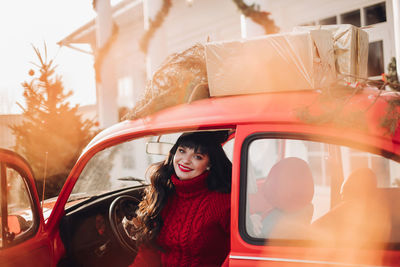 Portrait of a young caucasian woman in a warm knitted red sweater outside smiles