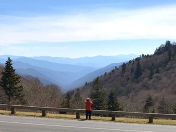 Man standing at a guard rail overlooking great smokey mountains national park