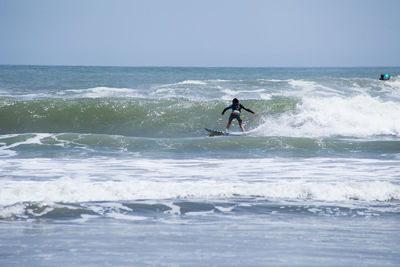 Man surfing on sea against clear sky