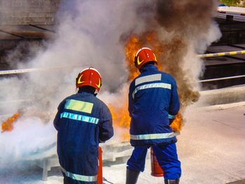 Rear view of firefighters extinguish fire on bridge