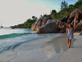 Full length of woman walking on beach against sky