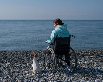 Disabled woman sitting on wheelchair at beach