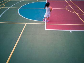 Full length of girl playing with basketball