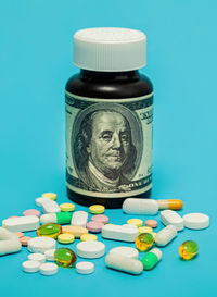 Money and pills of different colors on a blue background. the rise in the cost of medical care. the