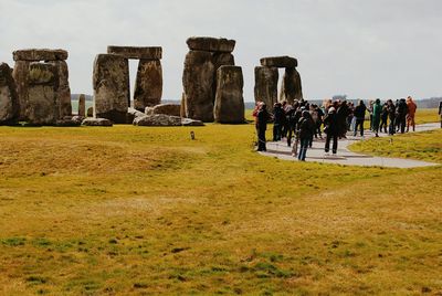 Tourist looking at stonehenge against sky