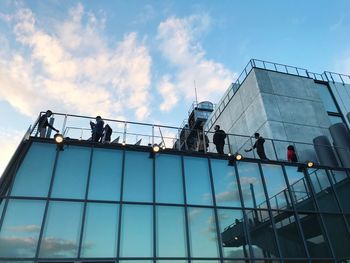 Low angle view of people working on glass building