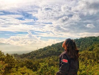 Rear view of woman standing on mountain against sky