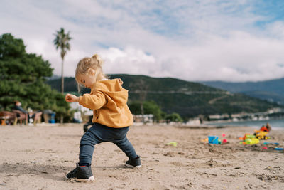 Full length of boy playing with arms outstretched standing at beach