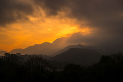 Scenic view of silhouette mountains against orange sky