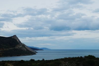 Scenic view of sea and mountains against cloudy sky