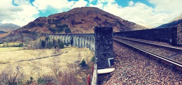 Railroad tracks by mountain against sky