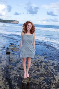 Portrait of smiling young woman standing on beach