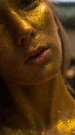 Close-up of young woman covered with gold glitter