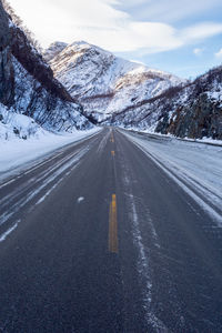 Road amidst snow covered mountain against sky