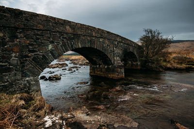 Arch bridge over river against sky