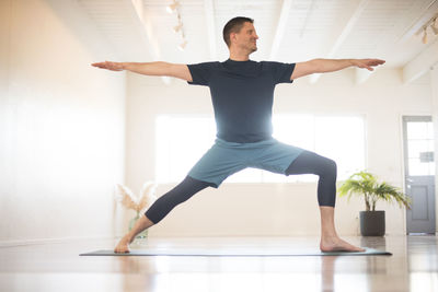 A guy in warrior 2 pose while practicing yoga.