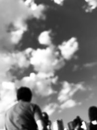 Rear view of man and woman standing against cloudy sky