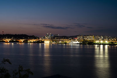 Seoul city at night, illuminated bridge over river against sky