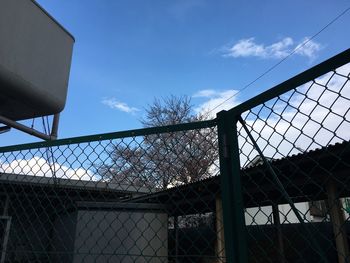 Low angle view of chainlink fence and building against sky