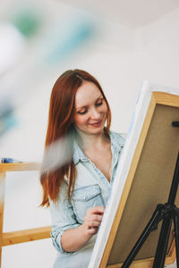 Woman painting while standing by railing