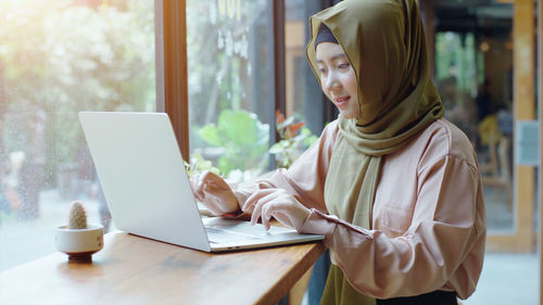 Young woman using mobile phone while sitting on table