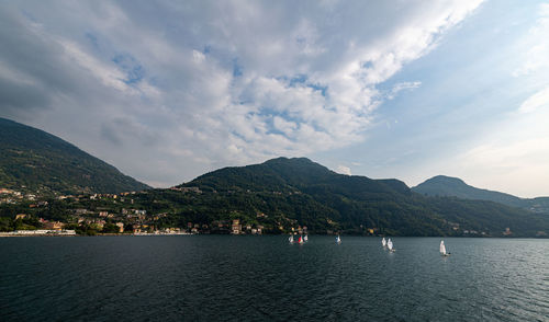 Scenic view of sea by mountains against sky