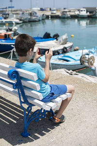 Rear view of boy sitting on seat in water