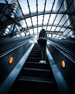 Rear view of man standing on escalator