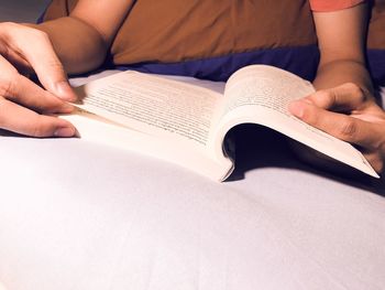 Midsection of person reading book on table