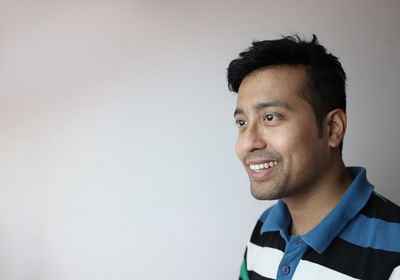 Portrait of smiling young man against gray background