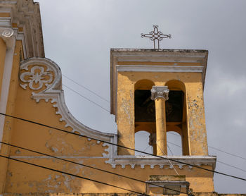 Low angle view of cross on building against sky