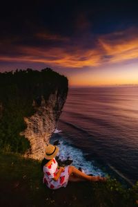 Woman enjoying the view of sea from cliff during sunset