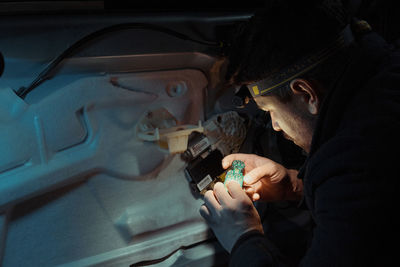 Close-up of man repairing vehicle at night