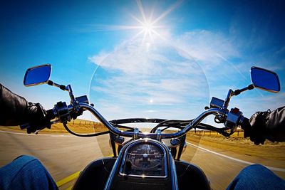 Motorbike speeding in front of long rural road against sun