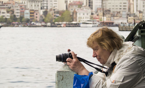 Side view of mature woman photographing straits