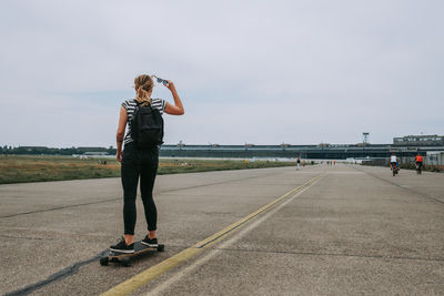 Rear view of woman standing on road against sky