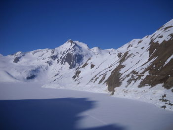 Scenic view of snowcapped mountains against clear blue sky