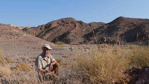 Senior man sitting in the desert 