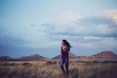 Full length of woman standing on field against mountains