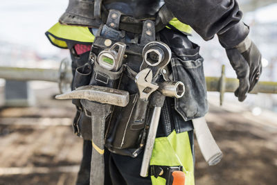 Midsection of construction worker wearing tool belt at site