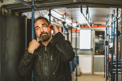 People, lifestyle, travel and public transport. attractive man talking on the phone in public bus .