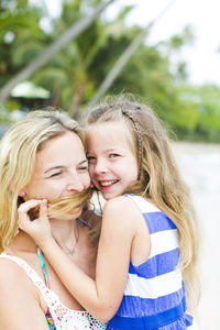 Portrait of smiling girl with mother at beach