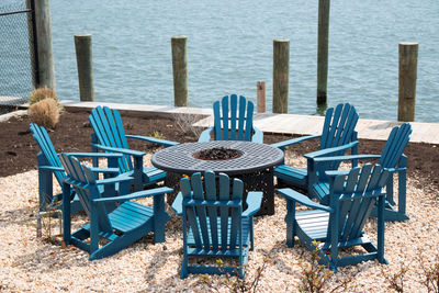 Empty chairs and table by sea