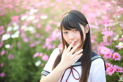 Portrait of smiling woman standing against pink flowering plants