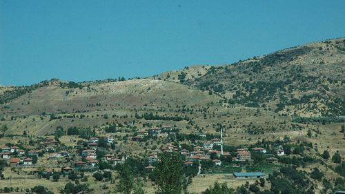 Aerial view of townscape and mountains against clear blue sky