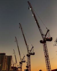 Low angle view of cranes at construction site against sky