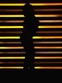 Close-up of silhouette man standing against yellow wall