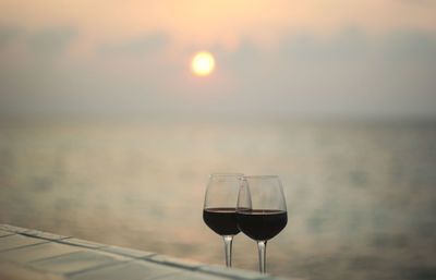 Close-up of wineglass on table against sky during sunset