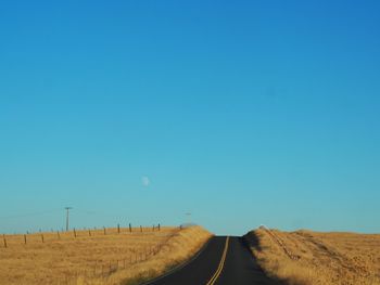 Road amidst landscape against clear blue sky